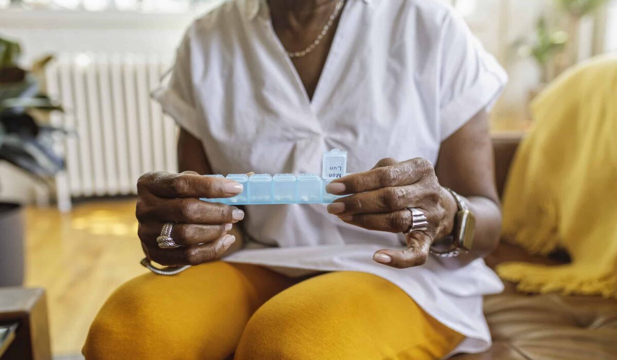 A patient takes medicine out of a daily pill box.
