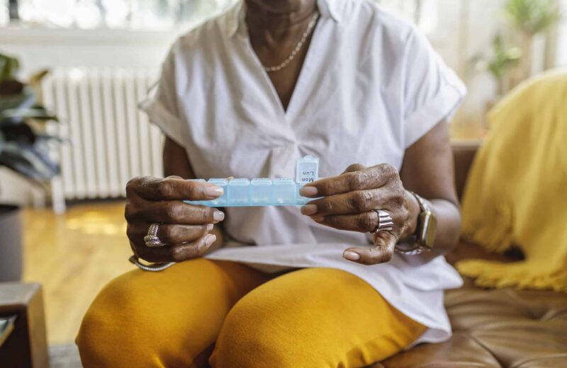 A patient takes medicine out of a daily pill box.