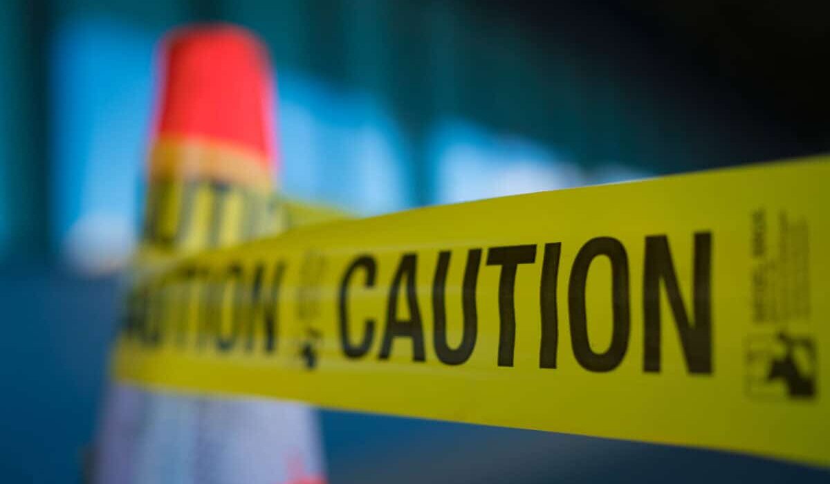 Yellow caution tape attached to traffic cone